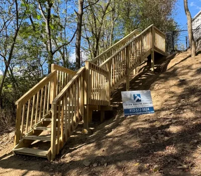 Custom-built wooden staircase designed for safe and durable access across a sloped landscape. custom wooden exterior staircase on hillside providing deck access in Pittsburgh PA