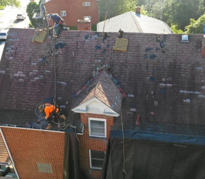 Active roof repair addressing damaged sections and restoring the integrity of the roofing system. Roof repair crew working on residential home roof in Pittsburgh PA with visible wear and tear